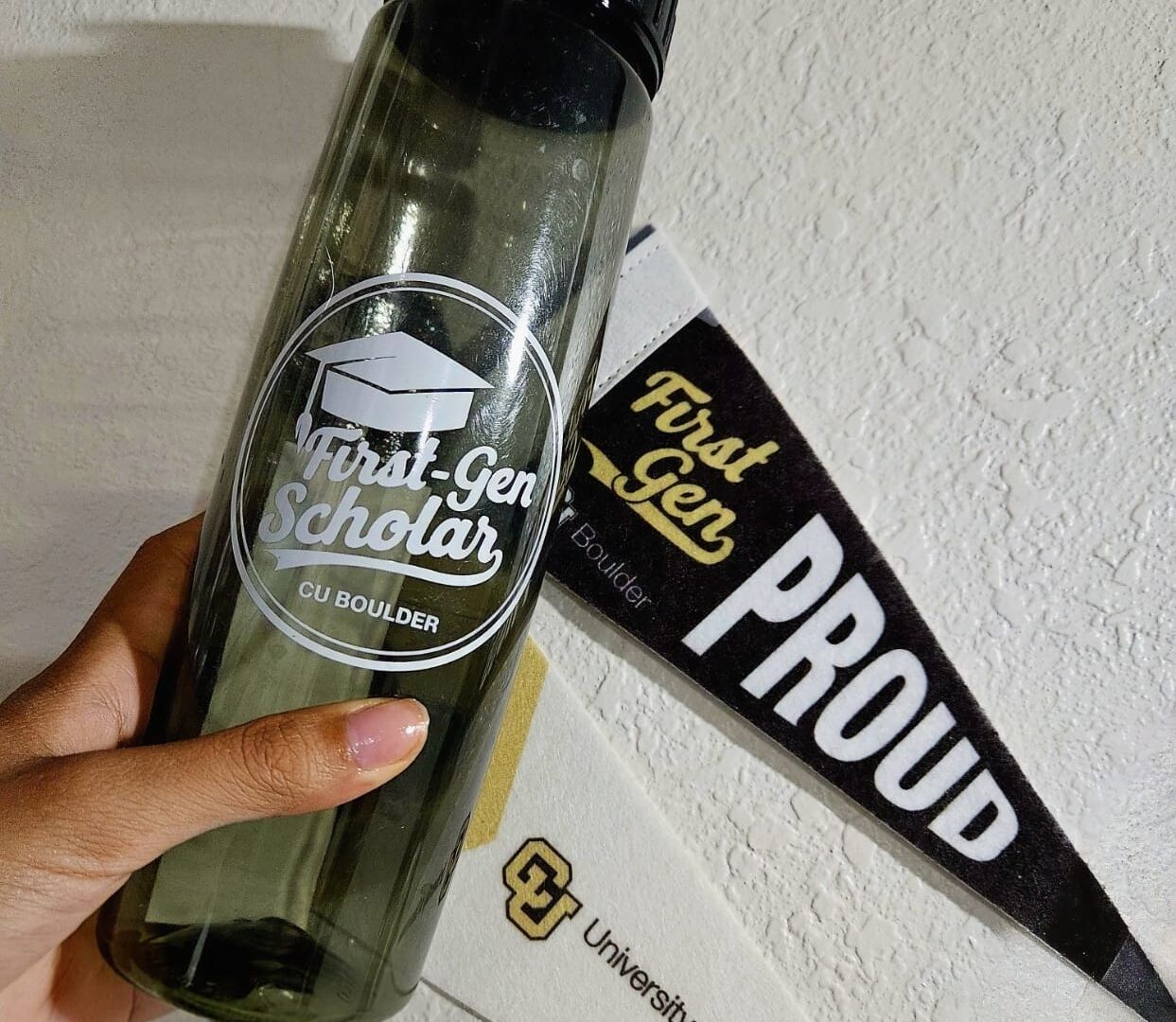 First-gen merch at CU Boulder A look at merchandise distributed at CU Boulder’s First-Generation Student Kickoff event, including a water bottle and a “Proud to Be First Gen” pennant. (Photo by Danielle Nguyen)