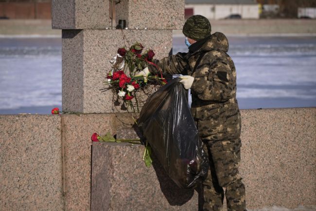An unidentified person removes flowers at the Memorial to Victims of Political Repression in St. Petersburg, Russia, on Feb. 19, 2024. (Dmitri Lovetsky for AP)