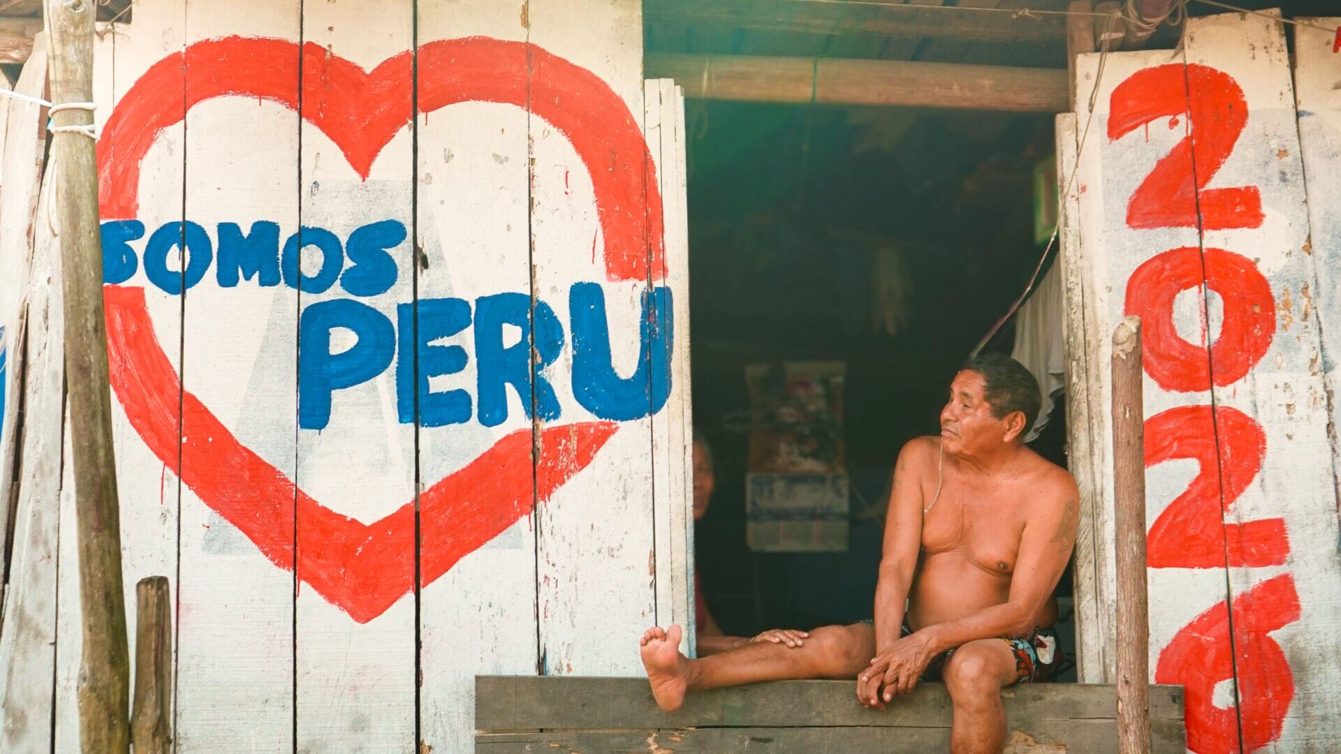 A man sits outside of his front door taking in the afternoon sun, with his wife in the background, in the Belén neighborhood of Iquitos, Peru, . Captured on February 28, 2026. (Photo by Will King)