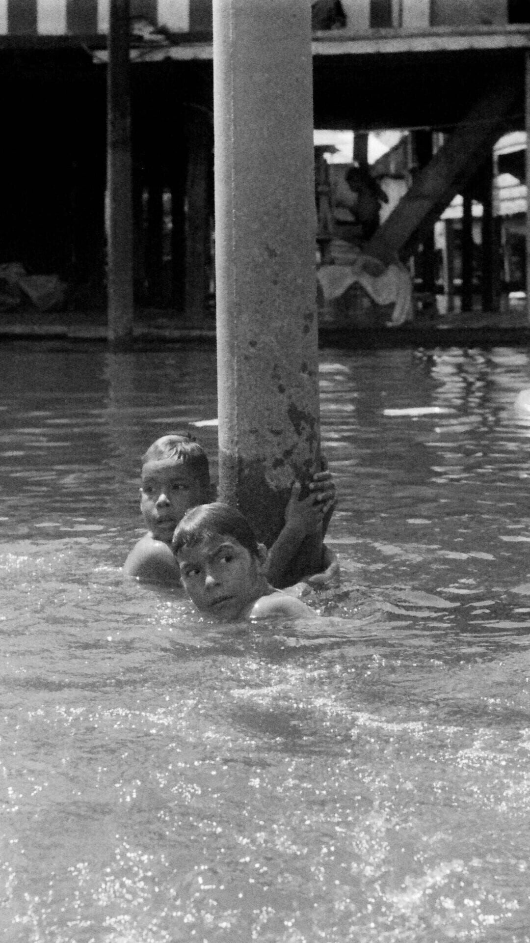 Two young boys cling to a street pole as they swim through the canals of Belén, a neighborhood of Iquitos, Peru, on Feb. 28, 2026. (Photo by Will King)